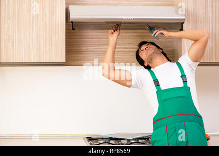 Young contractor repairing air-conditioner in kitchen Stock Photo