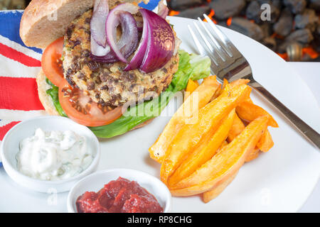 Homemade Quorn burger in a sourdough bun with lettuce, tomato, red onion, Sweet potato chips/fries, and served with ketchup and soy yogurt dips. Stock Photo