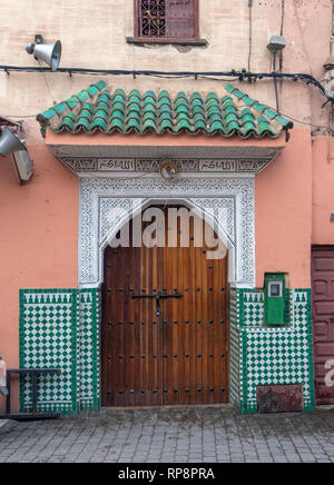 Traditional Moroccan style design of an ancient wooden entry riad door. In the old Marrakech, Morocco. Typical, old, brown intricately carved, studded Stock Photo