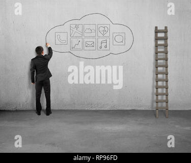 Businessman standing and drawing app icon on concrete wall background Stock Photo