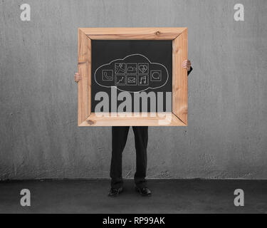 Man holding blackboard with hand-drawn cloud app icons in concrete room background Stock Photo