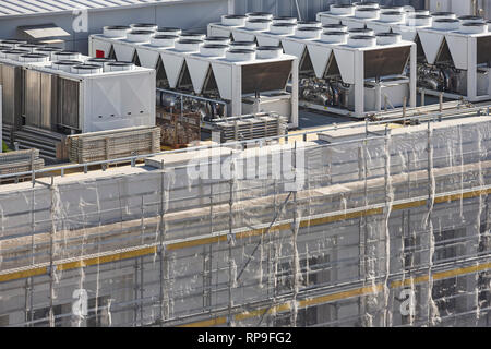 Air conditioner compressors on a building rooftop under construction. Industrial Stock Photo