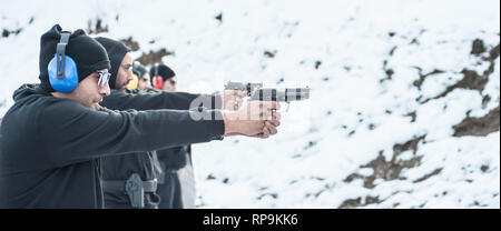 Group of civilian practice gun shoot on target on outdoor shooting range. Civilian team weapons training Stock Photo