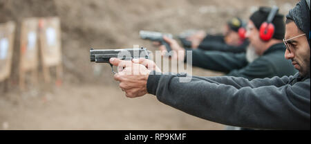 Group of civilian practice gun shoot on target on outdoor shooting range. Civilian team weapons training Stock Photo