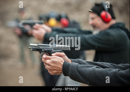 Group of civilian practice gun shoot on target on outdoor shooting range. Civilian team weapons training Stock Photo