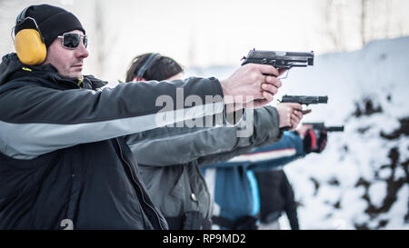 Group of civilian practice gun shoot on target on outdoor shooting range. Civilian team weapons training Stock Photo