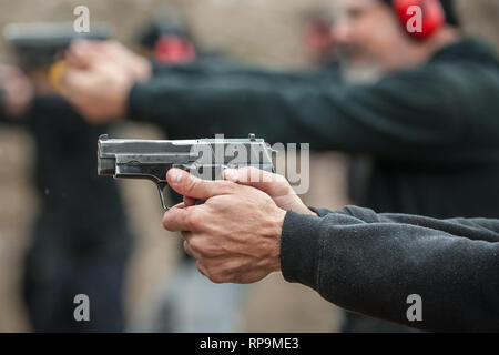 Group of civilian practice gun shoot on target on outdoor shooting range. Civilian team weapons training Stock Photo