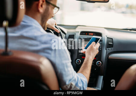 Man looking at mobile phone while driving Stock Photo