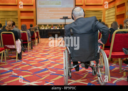 Group of business people attending press conference or presentation. Disabled businessman .Disabled Mature Businessman Sitting Near The Businesswoman  Stock Photo