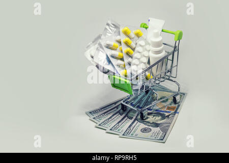 Shopping cart full of drug and medicine pills on dollar money, pharmaceutical cost concept. medications in the cart. buying medicines Stock Photo