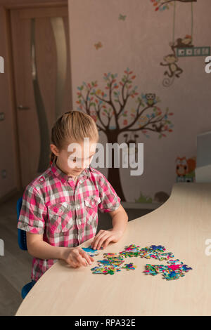 Cute little girl solving puzzle together sitting at the table Stock Photo