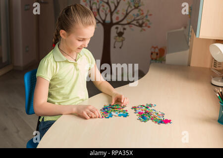 Cute little girl solving puzzle together sitting at the table Stock Photo