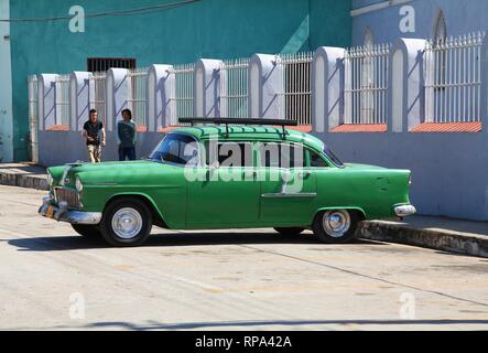 SANCTI SPIRITUS, CUBA - FEBRUARY 6: People walk by old American car in the street on February 6, 2011 in Sancti Spiritus, Cuba. Cuba has one of the lo Stock Photo