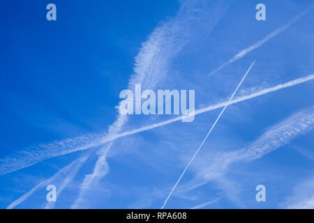 Abstract patterns of vapour trails in the blue sky, sometimes known as contrails or condensation trails. Stock Photo