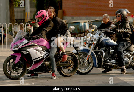 April 11, 2018 - Beijing, China - A Chinese woman rides on an imported Japanese Kawasaki motorcycle with a foreign man in Beijing on April 11, 2018.  Due to serious, daily traffic problems - old roads with millions of new cars - more and more Chinese and foreigners are buying motorcycles. . (Credit Image: © Todd Lee/ZUMAprilESS.com/ZUMA Wire) Stock Photo