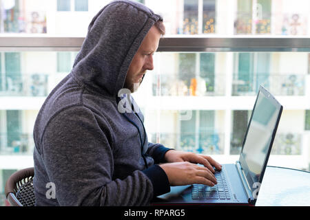 Cybercrime, hacking and technology concept - male hacker writing code or using computer virus program for cyber attack Stock Photo