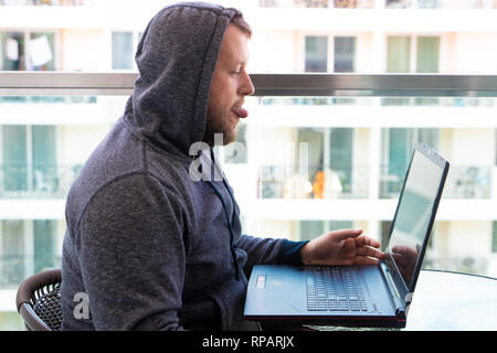Cybercrime, hacking and technology concept - male hacker writing code or using computer virus program for cyber attack Stock Photo