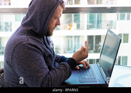 Cybercrime, hacking and technology concept - male hacker writing code or using computer virus program for cyber attack Stock Photo