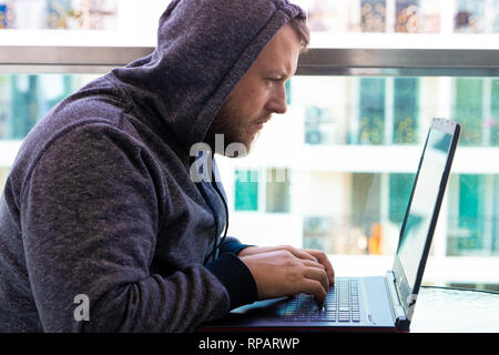 Cybercrime, hacking and technology concept - male hacker writing code or using computer virus program for cyber attack Stock Photo