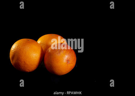 Three red oranges on a black background - image Stock Photo