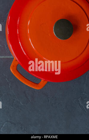 Orange traditional ceramic roasting dish with lid on a grey tile kitchen worktop Stock Photo