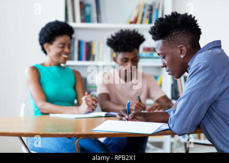 Female teacher learning with african american students at classroom of school Stock Photo