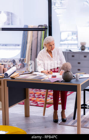 Charming silver-haired aging executive working at the table in office. Stock Photo