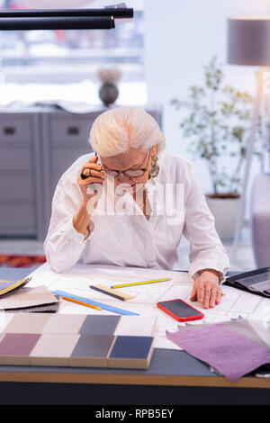 Charming aging leading designer concentratedly making a drawing in office. Stock Photo