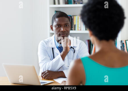 African american doctor listening to female patient at hospital Stock Photo