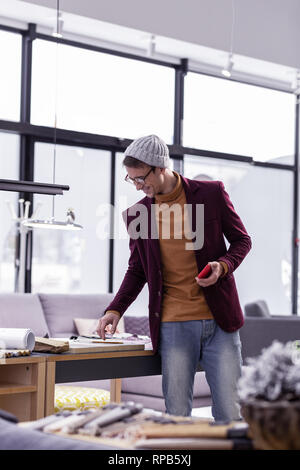 Nice-looking fancy male designer checking papers at office desk Stock Photo