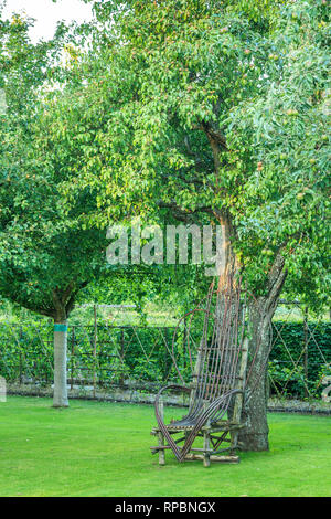 Orsan priory garden, France : armchair in wooden branches along a pear tree in the Apple Trees Orchard (obligatory mention of the garden name and no a Stock Photo