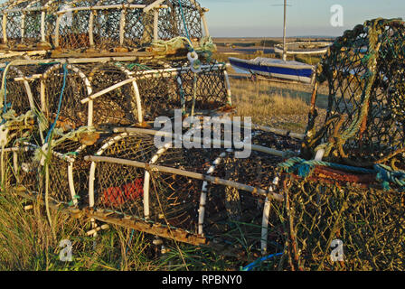 Lobster and crab pots stacked on the shingle at Brancaster Staithe, North Norfolk, UK Stock Photo