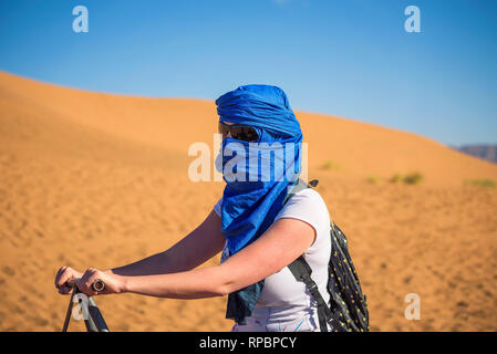 Tourist rides a camel through the sand dunes in the Sahara desert Stock Photo