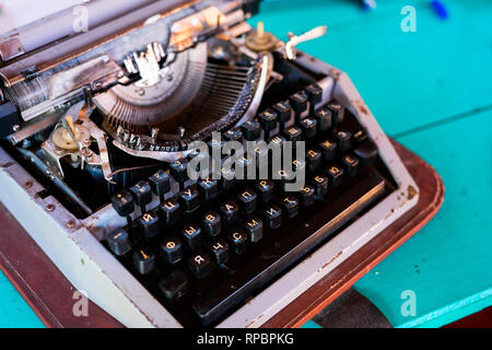 Old fashion typewritter on blue wooden background. Close up of vintage russian typewritter machine with Cyrillic. Selective focus . Stock Photo
