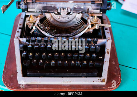 Old fashion typewritter on blue wooden background. Close up of vintage russian typewritter machine with Cyrillic. Selective focus . Stock Photo
