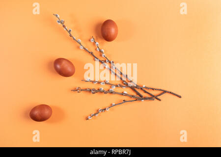 Easter composition of  eggs and willow branches on yellow-orange background.  Stock Photo