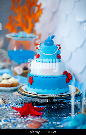 Huge blue and white birthday cake with sweet crab, fish, starfish and funny whale on the top. Summer season delicious on the party. Sea time theme on  Stock Photo