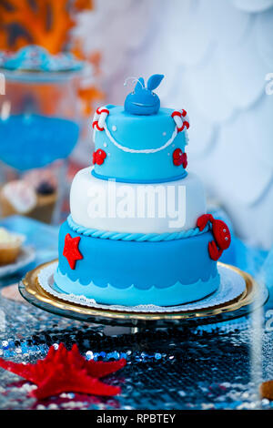 Huge blue and white birthday cake with sweet crab, fish, starfish and funny whale on the top. Summer season delicious on the party. Sea time theme on  Stock Photo