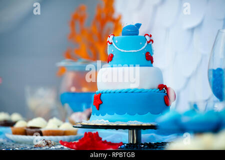 Huge blue and white birthday cake with sweet crab, fish, starfish and funny whale on the top. Summer season delicious on the party. Sea time theme on  Stock Photo