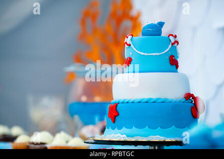 Huge blue and white birthday cake with sweet crab, fish, starfish and funny whale on the top. Summer season delicious on the party. Sea time theme on  Stock Photo