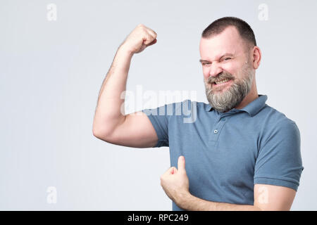 Handsome middle age european bearded man over showing arm muscle Stock Photo