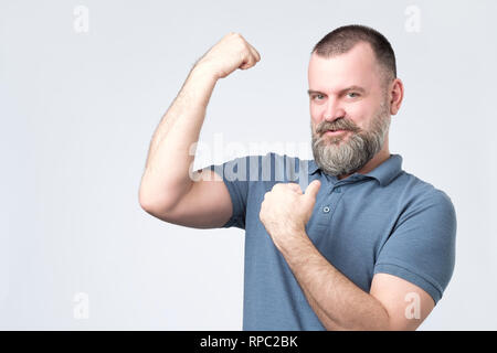 Handsome middle age european bearded man over showing arm muscle Stock Photo