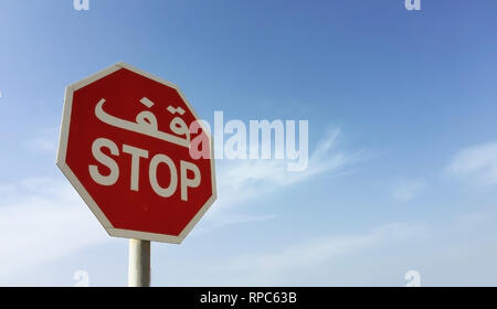 A red octagonal stop warning sign with Arabic text against blue sky Stock Photo