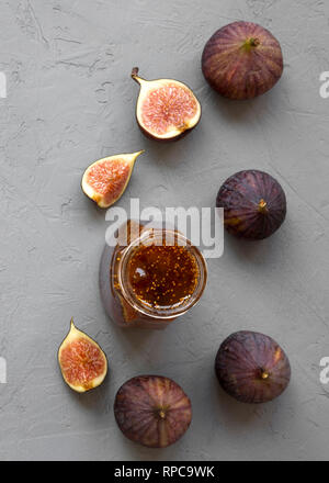 Fig jam in glass jar and fresh figs on gray background, top view. Flat lay, from above, overhead. Stock Photo