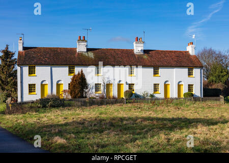 A row of six pretty Kent cottages all painted in a dark rich yellow paint, on a road junction of Back Lane, Near Hadlow, Kent, UK Stock Photo