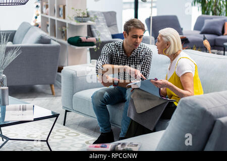 Charming aging lady discussing fabric samples with son in store Stock Photo