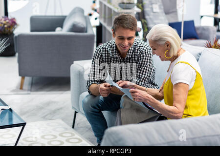 Alluring pleasant gentleman choosing fabric pieces with elderly fashionable mother Stock Photo