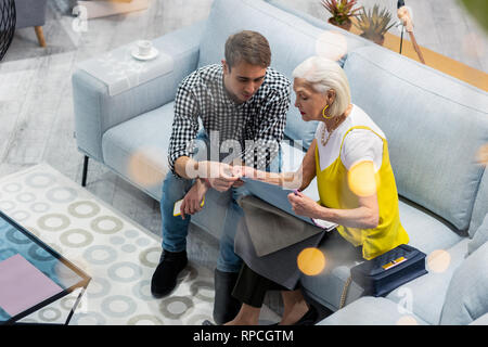 Blue-rinsed madam having conversation with son according couch textile selecting Stock Photo
