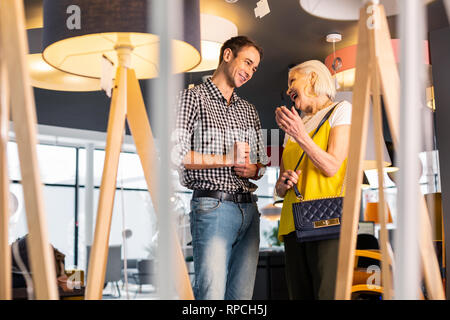 Cheerful mister joyfully chatting with elderly stylish woman in store Stock Photo