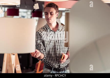 Overzealous nice-appealing client checking the lamps quality in showroom Stock Photo